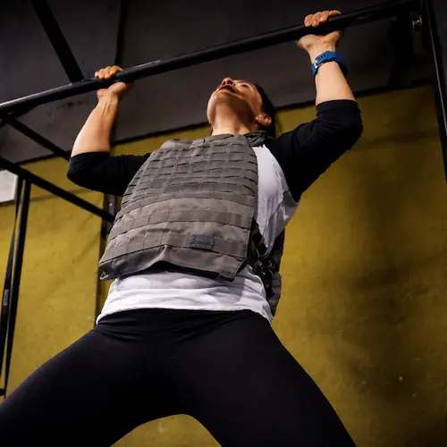 atleta de crossfit haciendo pull ups con chaleco lastrado